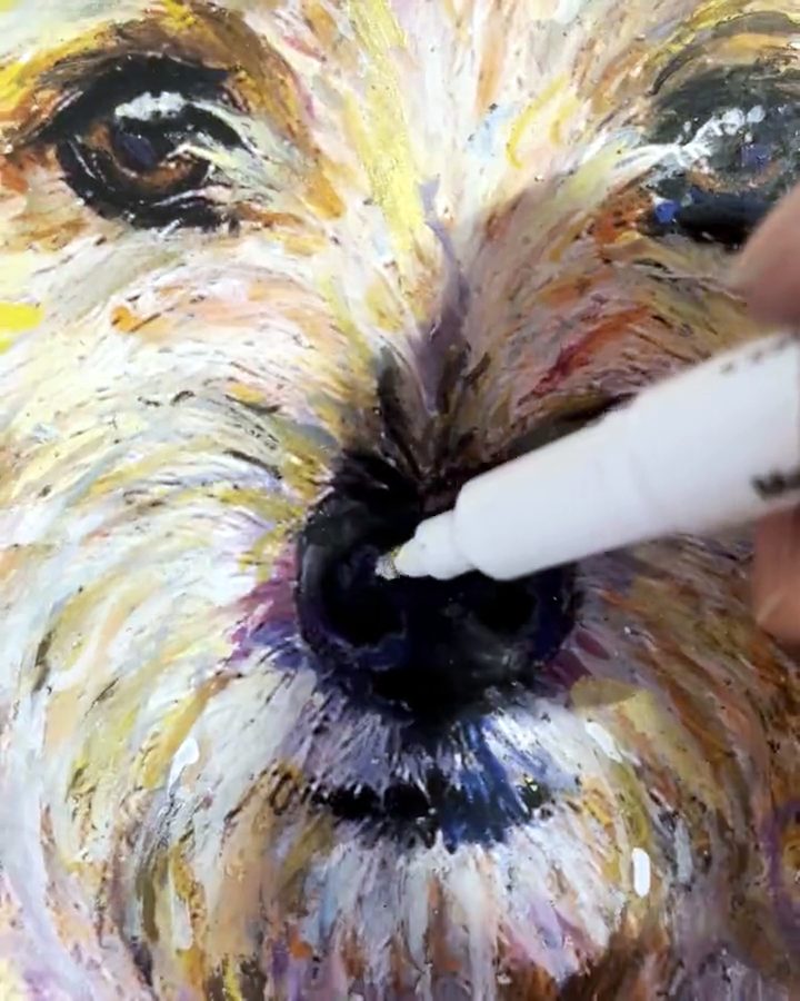 A hand working a stick of oil pastel into the ear of a painted portrait
